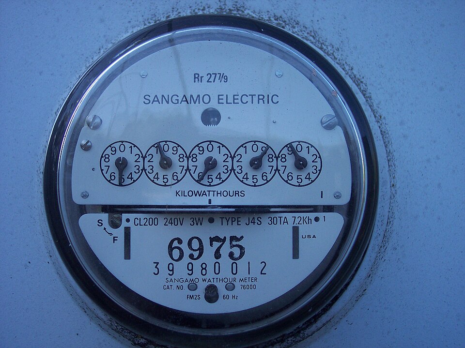 Older US electric meter with five numbered dials behind a round glass cover